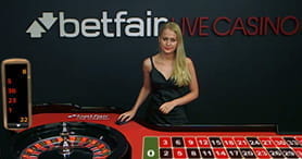 Das Bild zeigt einen Live Casino Tisch mit einer sympatischen Dealerin