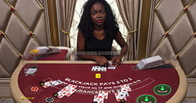 Ein weiblicher Croupier am Blackjack Tisch im Gate 777 Casino bei der Ausgabe der Karten im Spiel.