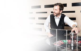 Ein Live Dealer steht an einem Roulette Tisch.