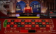 Auf diesem Bild sieht man eine junge Frau vor einem Roulettekessel. Vor ihr sind das Spielfeld sowie die Informationen zu den Einsätzen zu sehen.