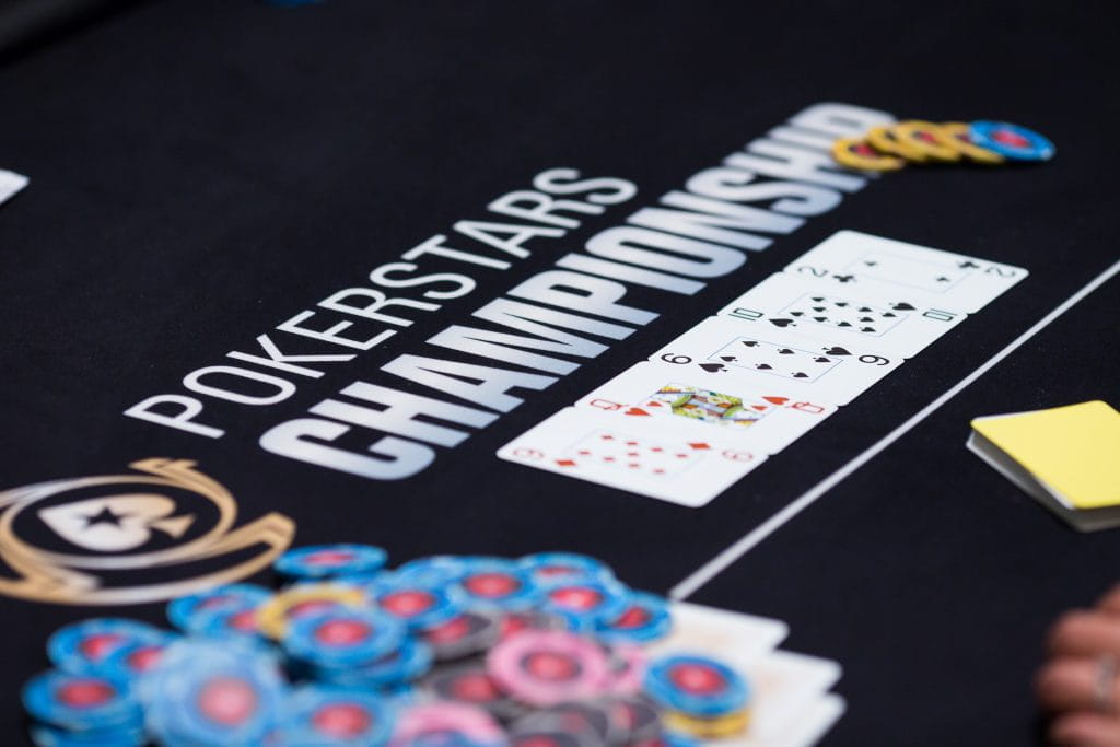 Der Turniertische bei einer Meisterschaft von Pokerstars mit fünf Spielkarten und Jetons.