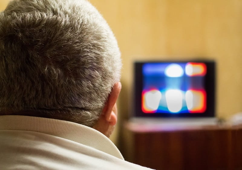Ein Mann verfolgt von der heimischen Couch eine TV-Show.