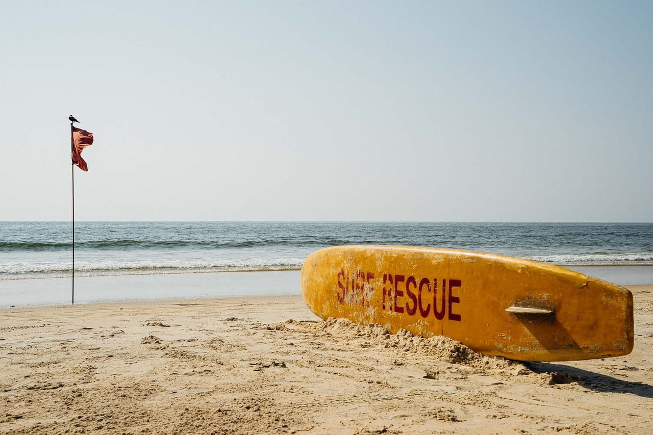 Surfbrett und Flagge an einem Strand in Goa..