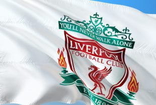 Eine weiße Fahne mit dem Wappen des FC Liverpools weht im Wind.