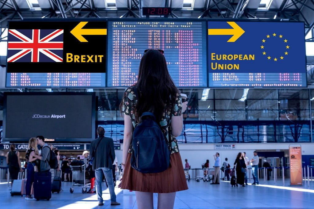 Frau am Flughafen befindet sich vor Bildschirmen mit den Kennzeichnungen Brexit und European Union.