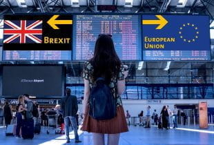 Frau am Flughafen befindet sich vor Bildschirmen mit den Kennzeichnungen Brexit und European Union.