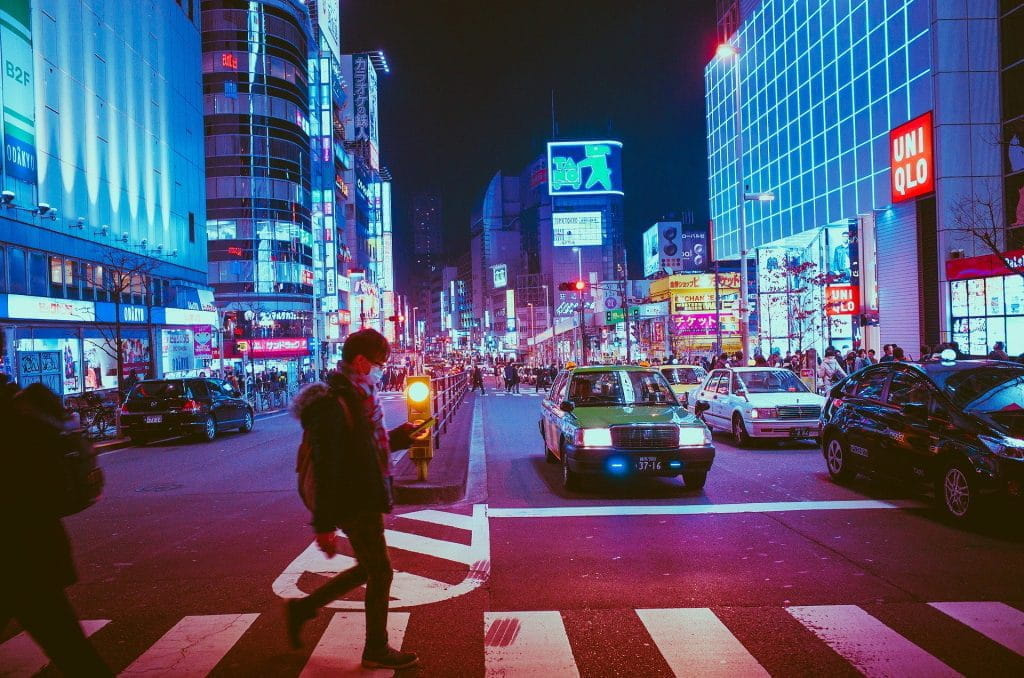 Belebte Straßenkreuzung in Osaka bei Nacht.
