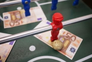 Ein Tischfußballfeld mit Spielfiguren und mehreren 50 Euro Scheinen.