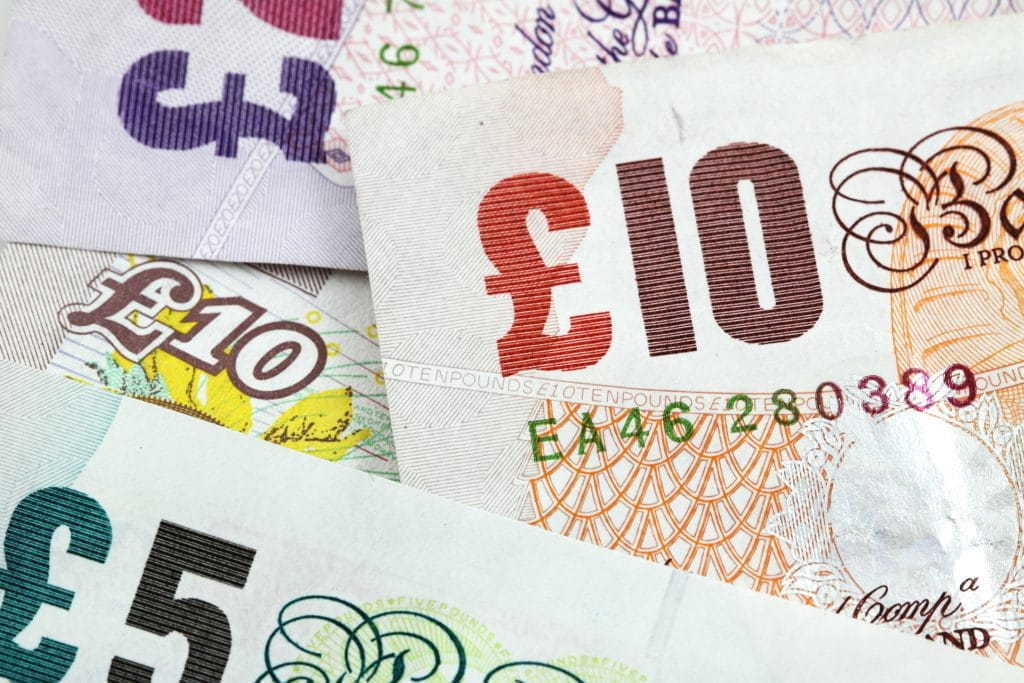 Britische Banknoten übereinander auf einem Haufen; obenauf 10 Pfund Sterling.