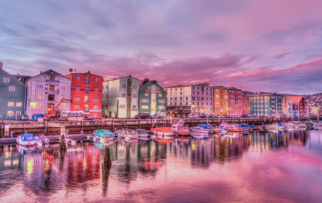 Bunte Wohnhäuser und zahlreiche Schiffe an einer Wasserfront in Trondheim in Norwegen.