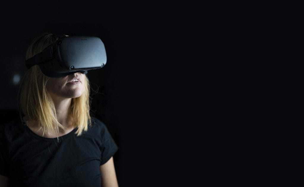 Eine Frau guckt mit einer VR-Brille auf dem Kopf in die Gegend.