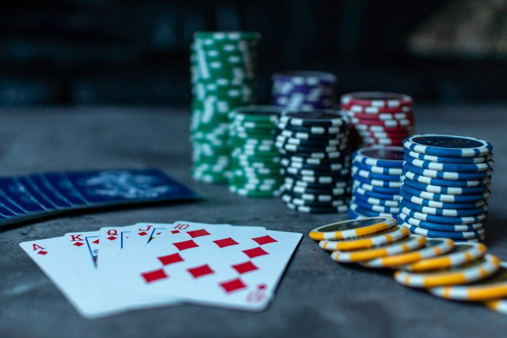 Verschiedene Stapel Pokerchips und Spielkarten auf einem Tisch.