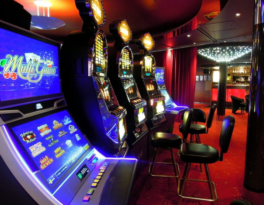 Fünf beleuchtete Glücksspielautomaten in einer Reihe in einer Spielbank.