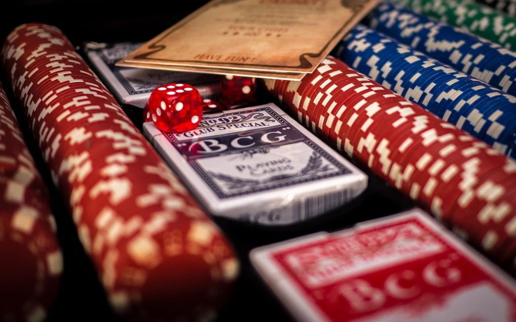 Pokerchips in mehreren Linien aufgereiht sowie Spielkarten und Würfel.