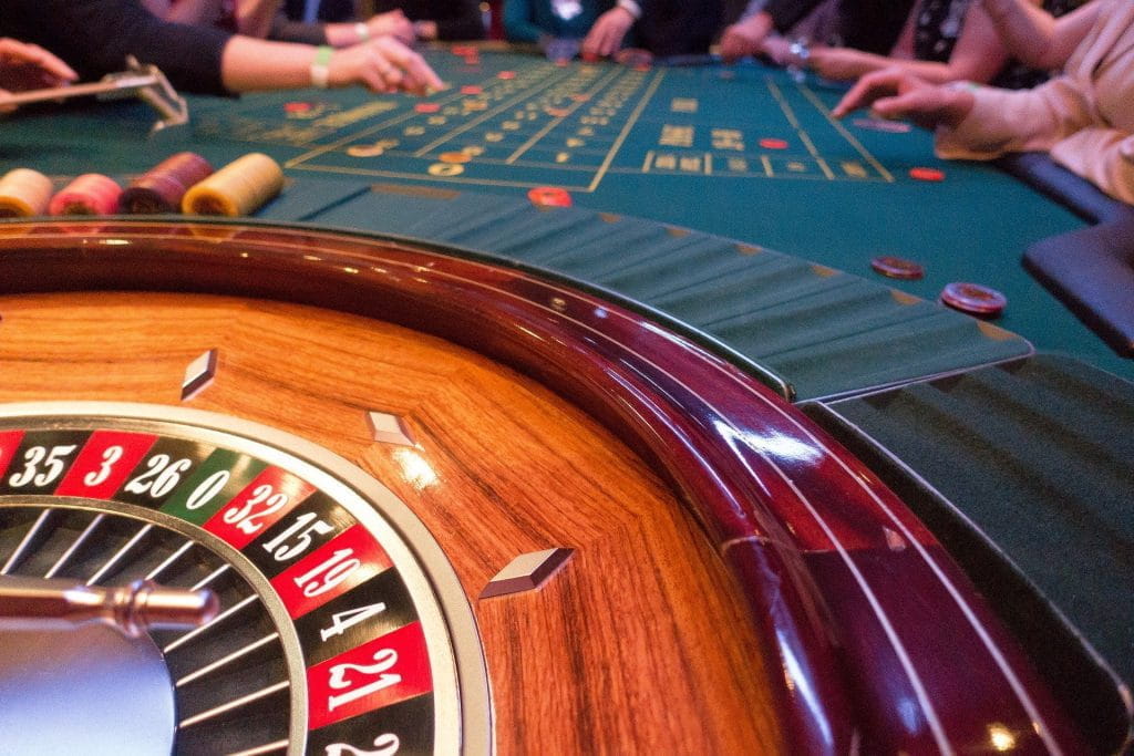Roulette-Kegel und -Tisch eines Casinos mit sitzenden Spielern und Jetons.