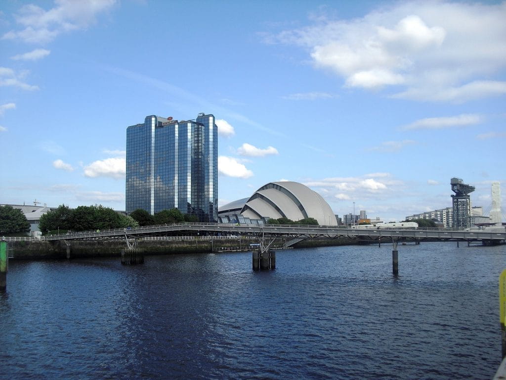 Mehrere Gebäude aus der Skyline Glasgows am Wasser.