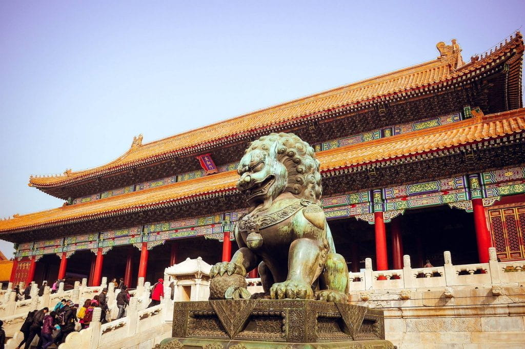Ein traditioneller chinesischer Tempel in Peking mit einer Löwenstatue davor.