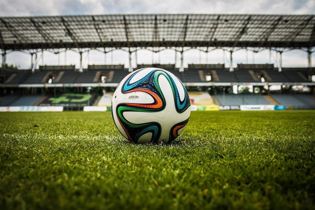 Ein Fußball liegt alleine auf einem Fußballfeld in einem leeren Stadion.