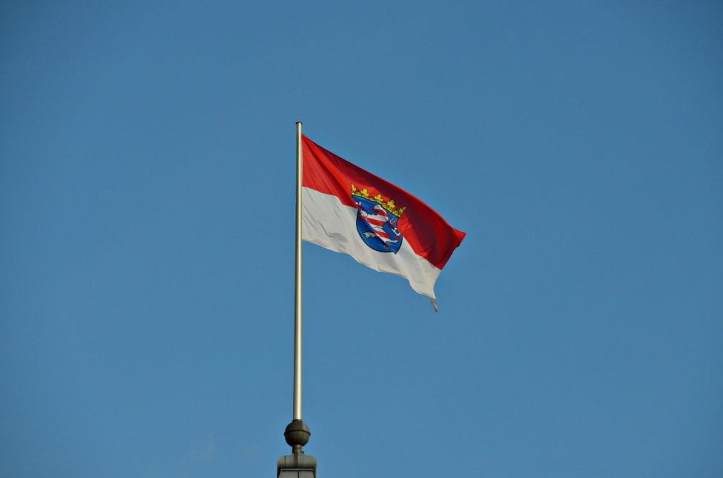 Fahne des Bundeslands Hessen unter blauem Himmel wehend im Wind.