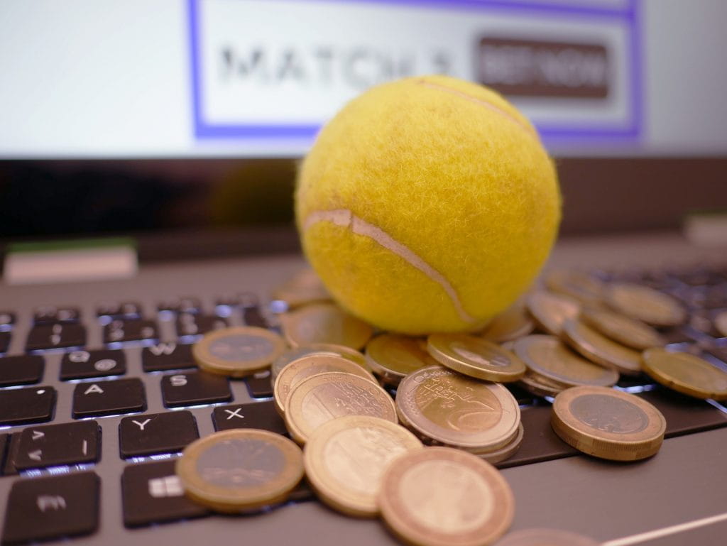 Ein Tennisball sowie verschiedene Euro-Münzen auf einer Laptop-Tastatur.