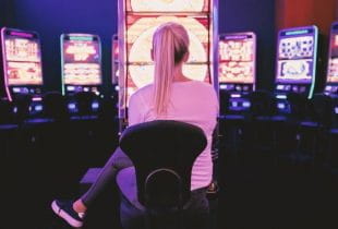 Frau sitzt vor einem Spielautomaten im Casino.