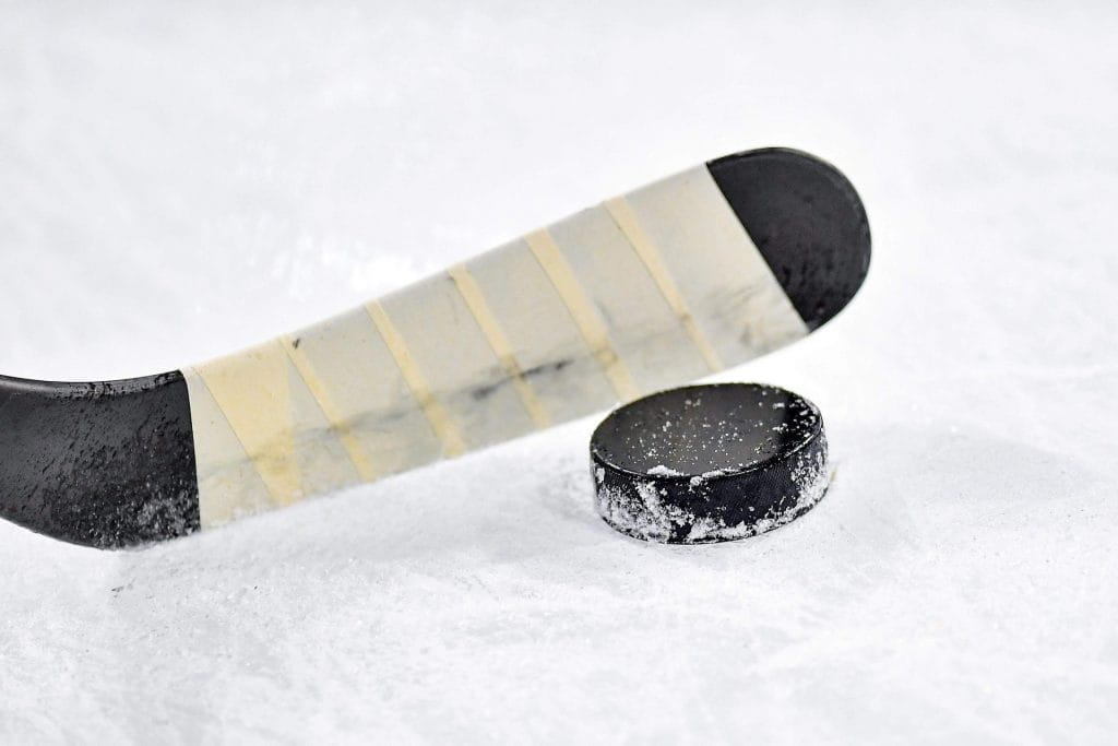 Eishockey-Schläger und Puck auf einer Eisfläche.