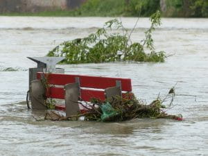 Eine Parkbank ragt aus Hochwasser heraus.