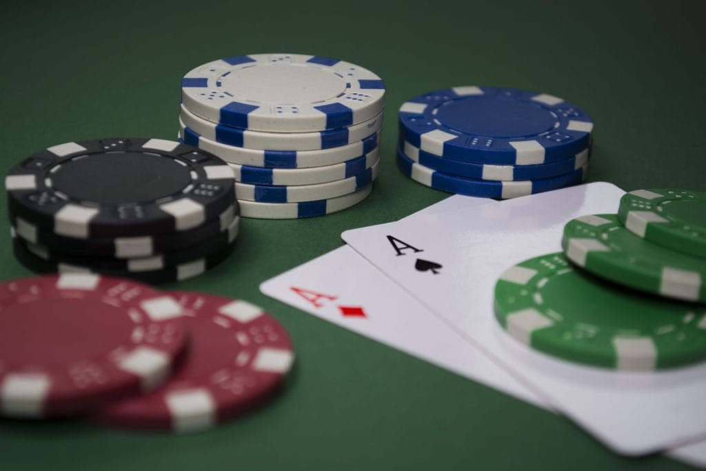 Dua kartu as di antara beberapa tumpukan chip poker.