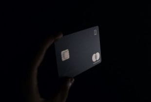 Eine Person hält eine schwarze Kreditkarte in der Hand.