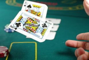 Ein Pokerspieler schmeißt eine Kartenhand mit zwei Königen auf Pokertisch.