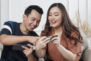 Zwei Personen zocken auf ihren Smartphones.