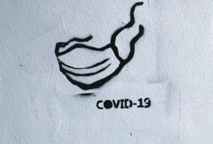 Ein Graffiti zeigt eine Maske und eine Covid-19-Aufschrift.