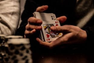 Eine Person mischt Karten an einem Pokertisch.