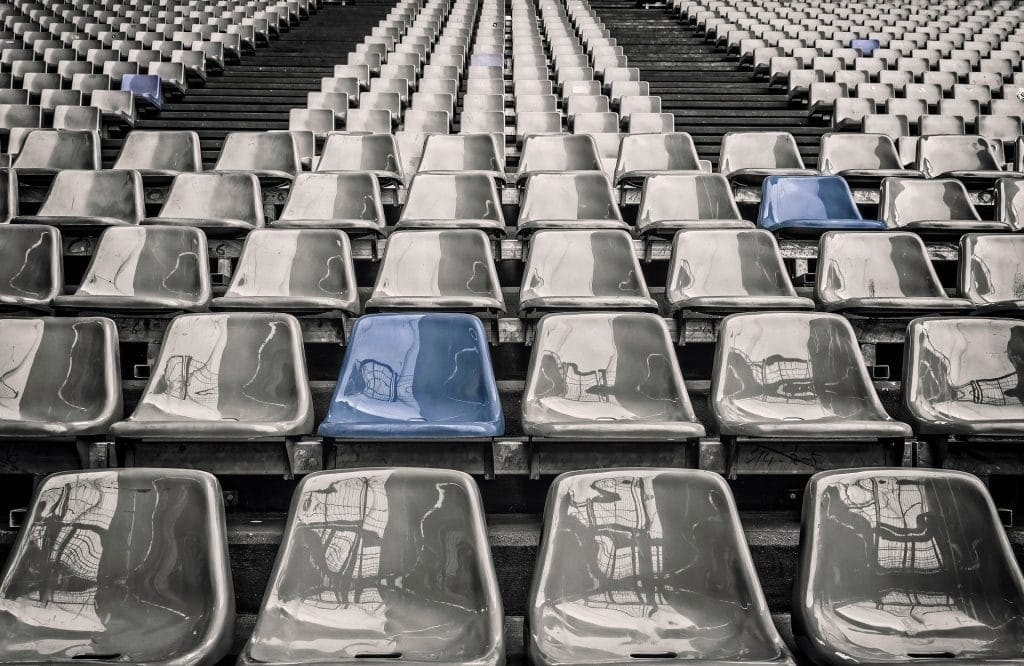 Mehrere Sitzreihen auf einer Stadiontribüne.