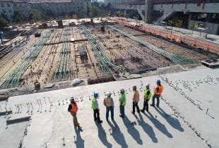 Bauarbeiter mit Warnwesten und Schutzhelmen auf einer Großbaustelle.