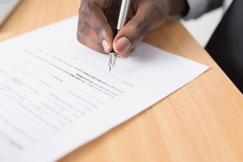 Eine Person unterschreibt mit einem Füller einen Vertrag.