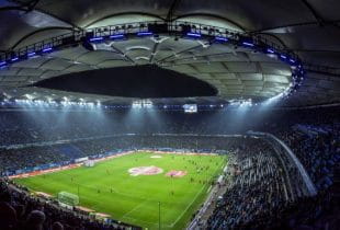 Ausverkauftes Volksparkstadion in Hamburg bei Nacht.