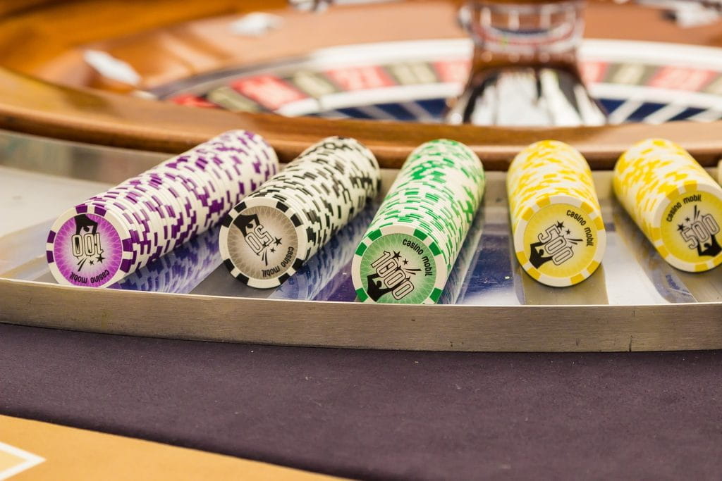 Gereihte Jetons neben einem Roulette-Kessel.