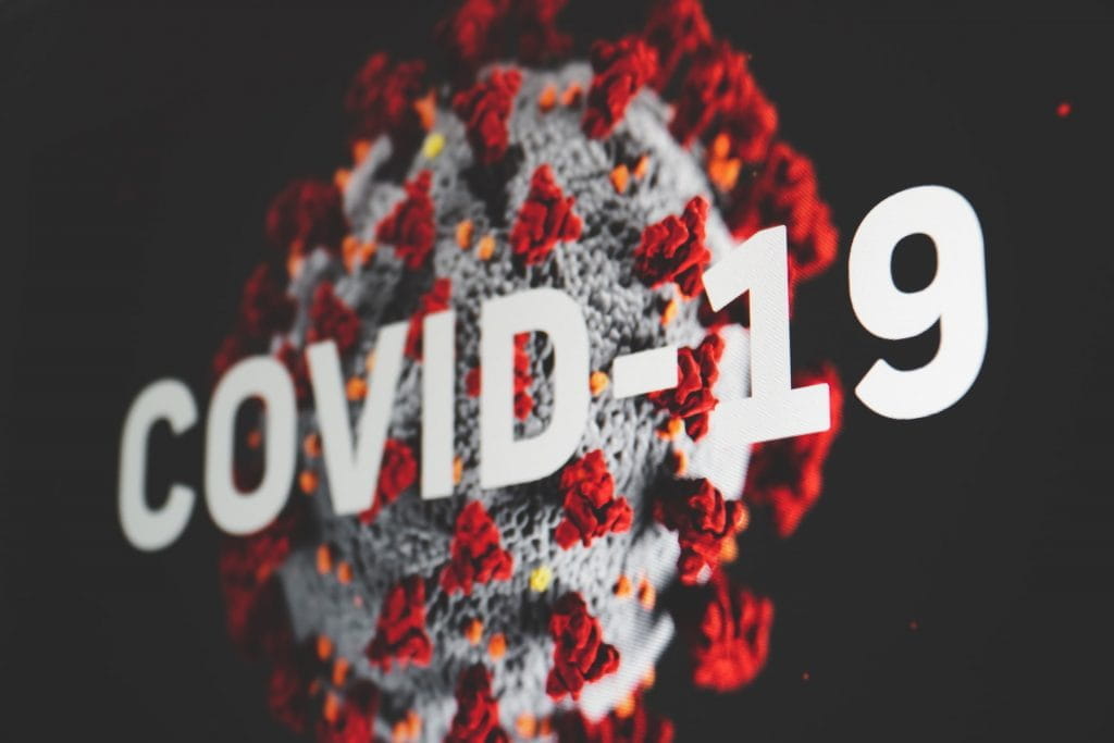 Coronavirus mit Schriftzug Covid-19 im Vordergrund.