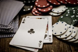 Eine Kreuz-Ass und eine Pik-Dame-Karte vor zahlreichen Spielchips.