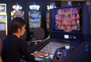 Eine Frau spielt an einem Automaten den beliebten Slot Book of Ra.