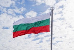 Die bulgarische Flagge an einem Fahnenmast bei bewölktem Himmel.