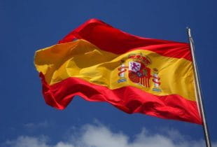 Die spanische Flagge weht an einem Fahnenmast im Wind.