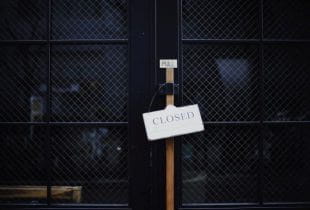 Closed-Schild hängt an einer Ladentür.