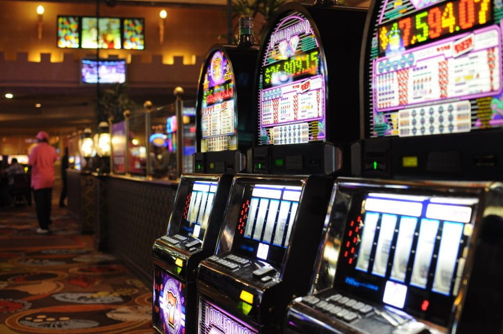 Drei Spielautomaten in einem terrestrischen Casino.