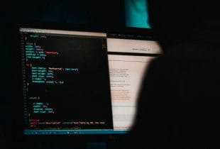 Die Silhouette einer Person hackt an einem PC.