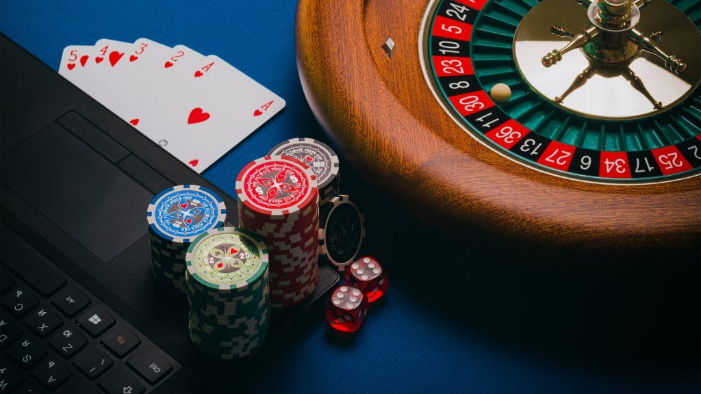 Keripik, kartu remi, dadu, dan roda roulette bersama dengan laptop.