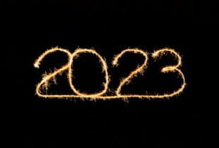 Die Zahl 2023 als leuchtender Schriftzug mit Funken auf schwarzem Hintergrund.