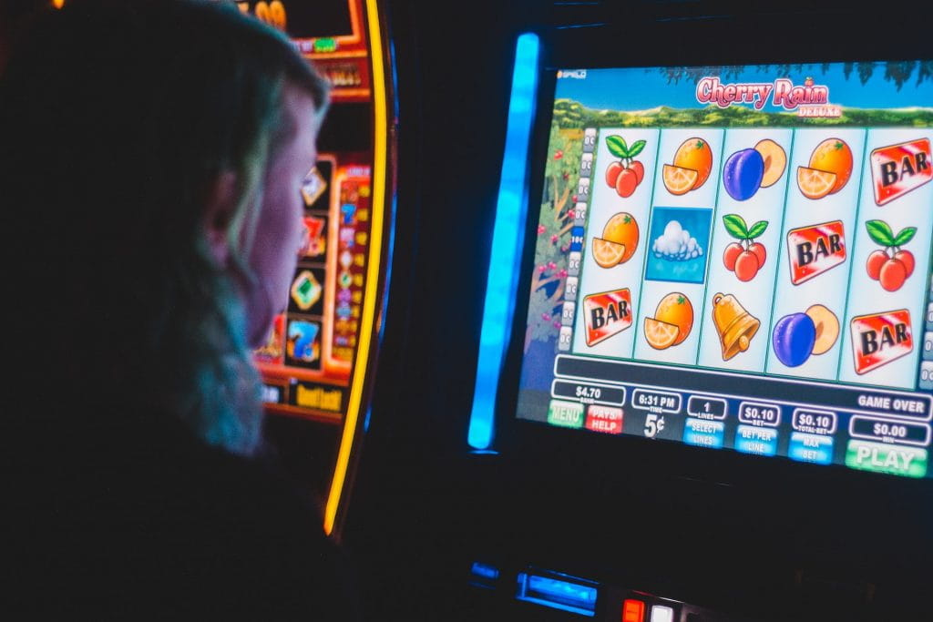 Seorang wanita memainkan mesin slot di arcade.