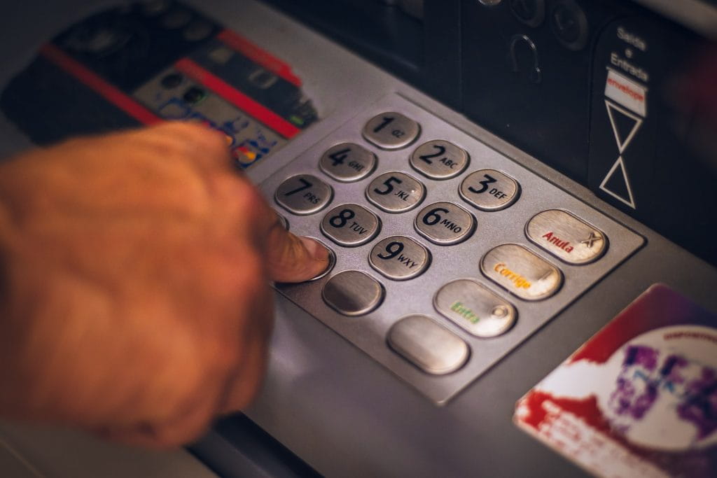Eine Person tippt einen Bank-PIN auf der Tastatur eines Geldautomaten ein.